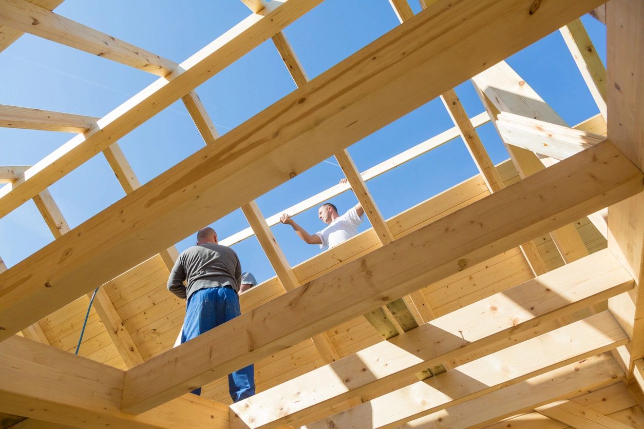 Two men are standing on a roof of a house.